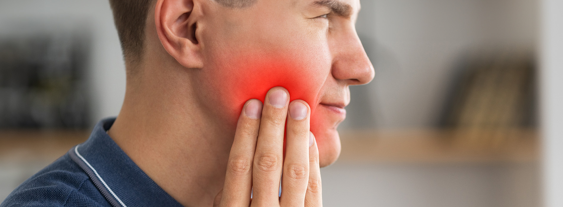 The image shows a man with a red blemish on his face, likely an acne or skin irritation, looking directly at the camera with a neutral expression.